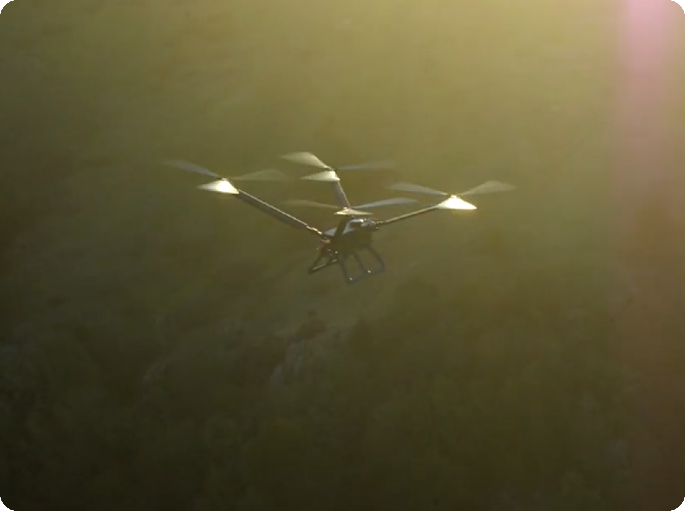 Drone with multiple propellers flying in a sunlit outdoor environment.